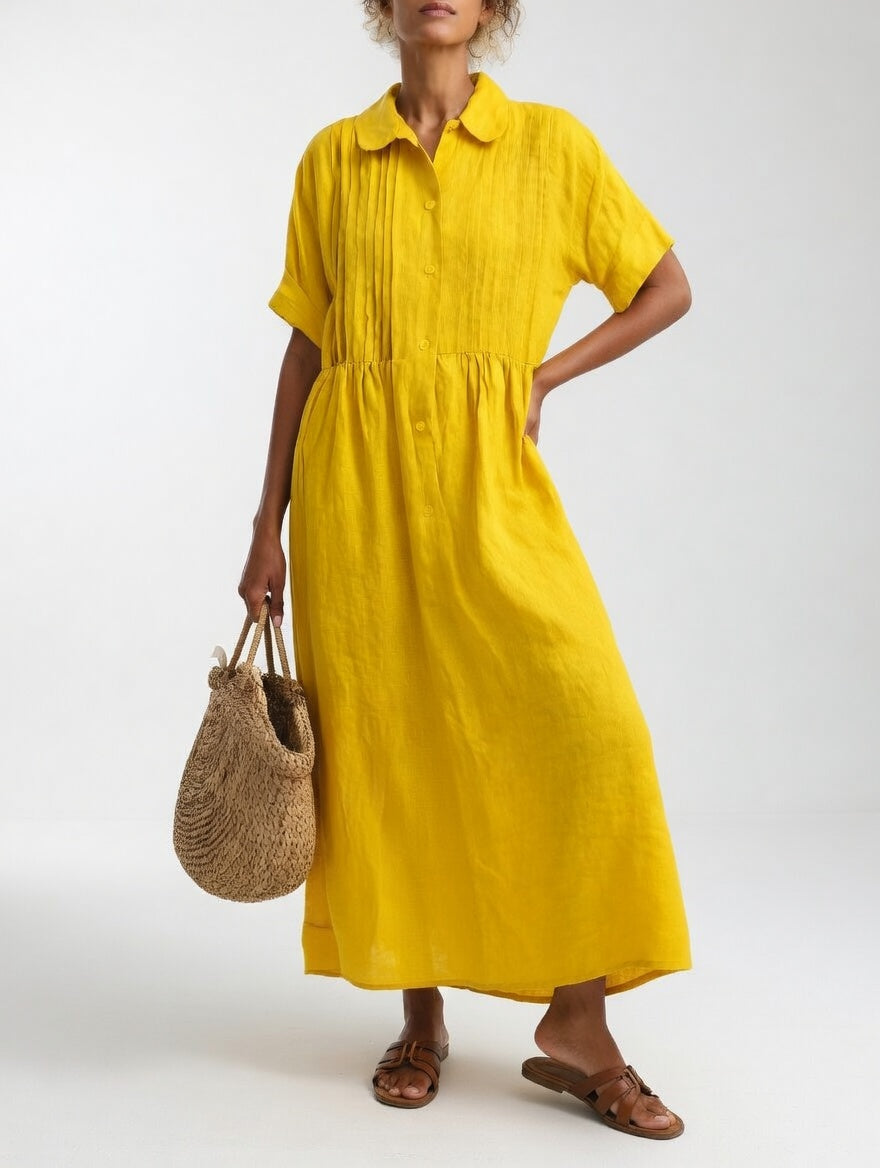 Model in de gele uitvoering, met een hand op de heup, rieten tas in de andere hand en bruine sandalen. 6