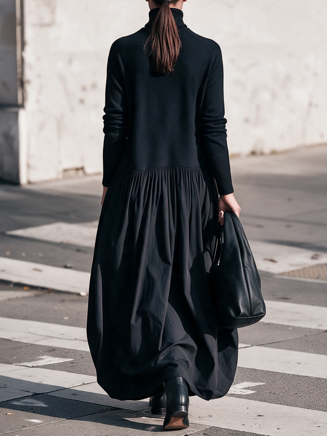 Achterkant van de zwarte jurk met gerimpelde taille en wijde rok, model loopt met paardenstaart 3