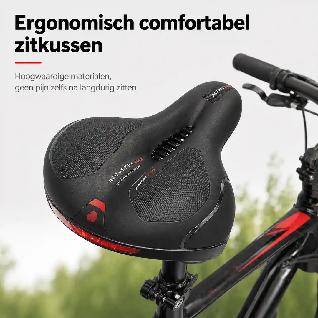 Zwart zadel met uitsparing en rode reflecterende strip, schuin van boven gezien op een fiets met groene begroeiing erachter. 1
