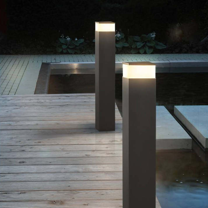 Twee zwarte lichtpalen bij avond op een houten terras naast een vijver, met warmwit licht in het bovenstuk. 8