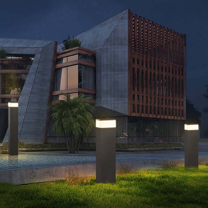Drie zwarte lichtpalen in het gras bij avond, voor een modern gebouw met houten gevelelementen. 6