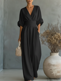 Model draagt de zwarte jumpsuit met V-hals en omgeslagen halve mouwen in een lichte studio 6