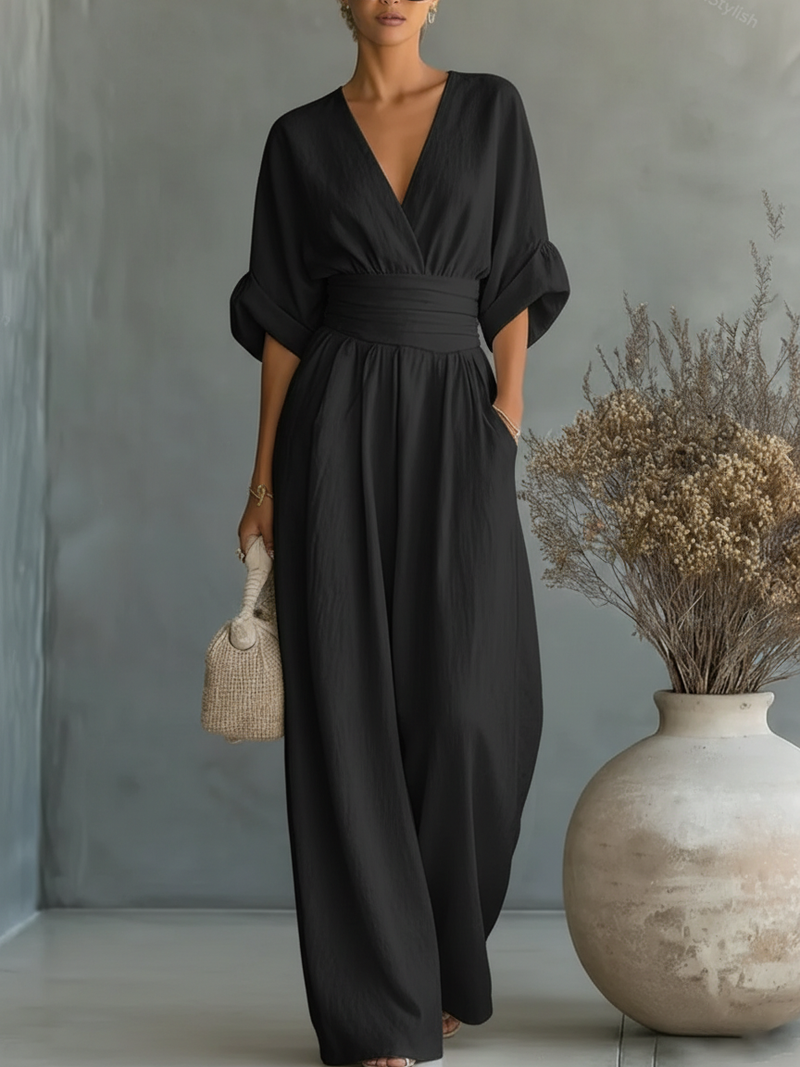 Model draagt de zwarte jumpsuit met V-hals en omgeslagen halve mouwen in een lichte studio 6