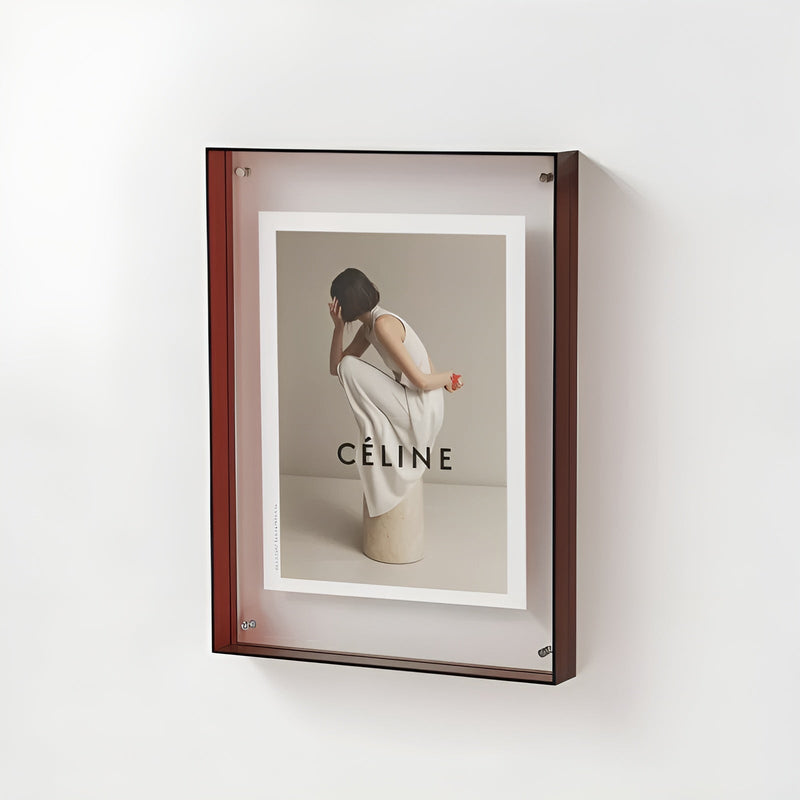 Rode acryl lijst met zwarte rand aan de muur, met een foto van een gehurkte vrouw in een wit jurkje. 20
