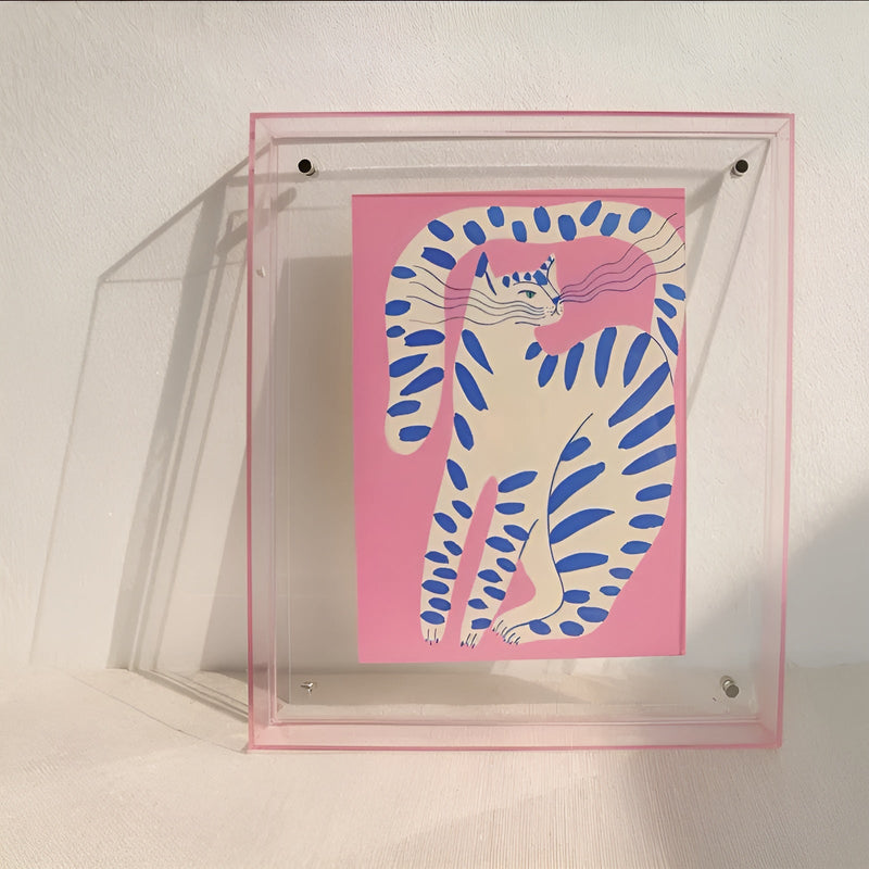Transparante acryl lijst met roze randje en een roze print van een witte kat met blauwe strepen. 9