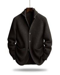 Zwart geribd vest aan een kleerhanger, met sjaalkraag, drie knopen en twee zakken, getoond van voren. 2
