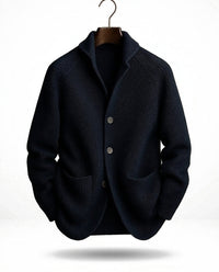 Donkerblauw geribd vest hangend aan een kleerhanger, met sjaalkraag, knoopsluiting en twee grote opgezette zakken. 3