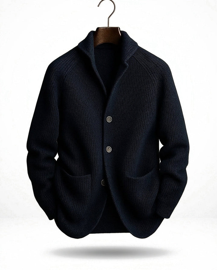 Donkerblauw geribd vest hangend aan een kleerhanger, met sjaalkraag, knoopsluiting en twee grote opgezette zakken. 3