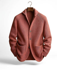 Terracottakleurig geribd vest aan een kleerhanger, met sjaalkraag, knoopsluiting en twee opgezette zakken aan de voorkant. 6