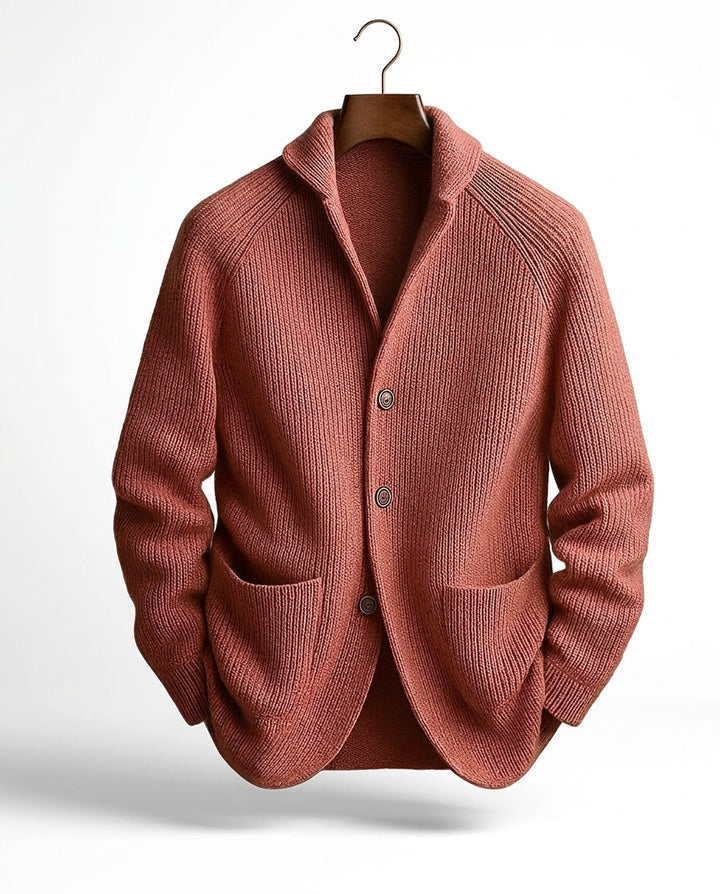 Terracottakleurig geribd vest aan een kleerhanger, met sjaalkraag, knoopsluiting en twee opgezette zakken aan de voorkant. 6