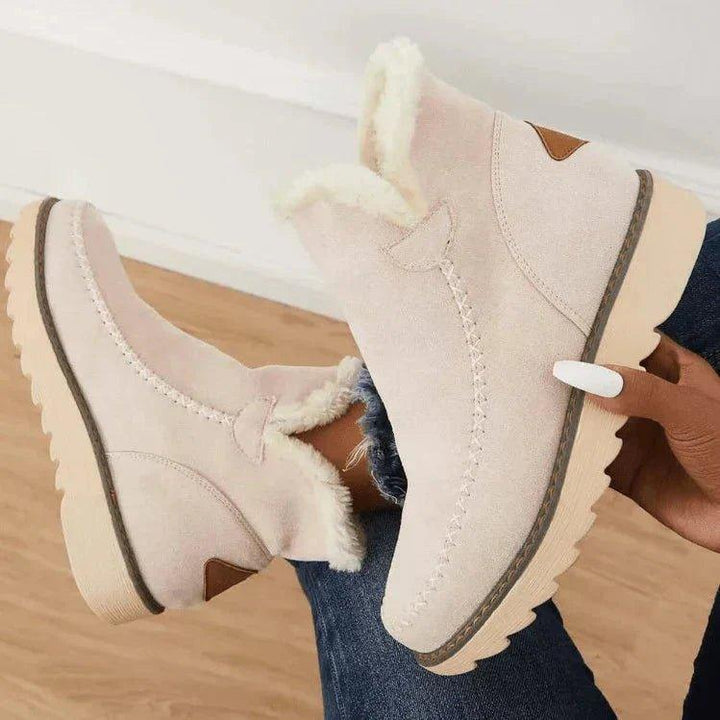 Beige enkellaarsjes in de hand gehouden, zijkant met pluche voering, bruin hielstukje en dikke lichte zool met profiel. 6