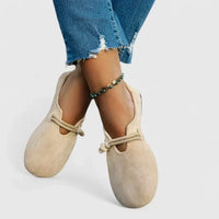 Beige loafers met touwdetail, gedragen met gekruiste benen en een enkelbandje met blauwgroene kralen 3