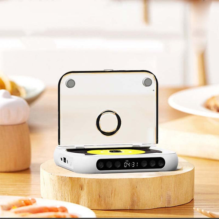 Witte speler met geopende doorzichtige klep voorop op een houten plateau, in een keuken met borden en eten op de achtergrond. 7