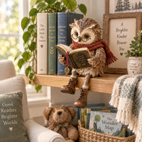 Uilbeeldje met bril en boek zit op een houten wandplank bij kinderboeken, een knuffelbeer en een mand met prentenboeken. 9