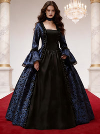 Model in blauwe gothische baljurk met zwart voorpaneel, ruches en uitlopende mouwen, in een marmeren zaal met kroonluchter. 2