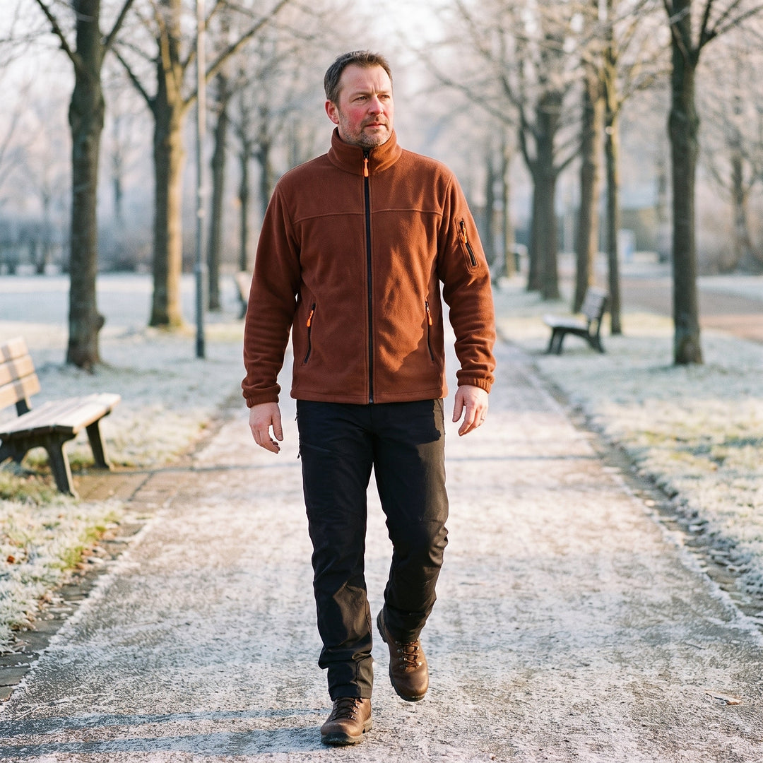 Man draagt de roestbruine fleecejack met zwarte broek tijdens een wandeling door een bevroren park 2