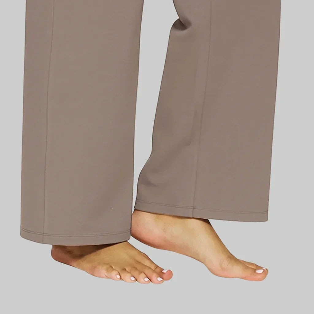 Detail van de broekspijpen onderaan in taupebruin, met omgenaaide zoom en naad aan de voorkant, model op blote voeten. 5