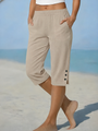 Model op het strand draagt de capribroek in beige, met handen in de zakken 1