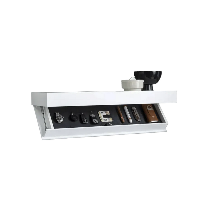 Witte wandplank met geopend verborgen vak met horloge, sleutels, geld en sigaren, met een zwarte schaal en pot erbovenop. 2