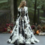 Model draagt de jurk met skeletprint in zwart met witte 3D-bloemen en lange mouwen, in een herfstachtig bos. 2