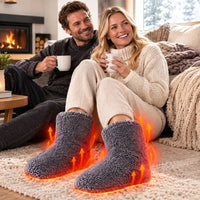 Lachend stel op de vloer met warme dranken; de grijze pantoffels hebben oranje pijlen die warmte aangeven. 5