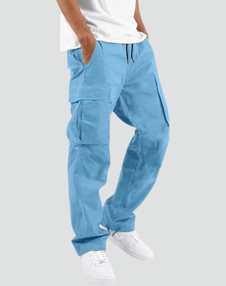 Model draagt de cargobroek in lichtblauw, met handen in de zakken, wit shirt en witte sneakers, voor een lichtgrijze achtergrond. 14
