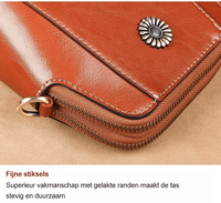 Close-up van de hoek met fijne stiksels, gelakte rand, rits, D-ring en bloemvormig sierstuk 16
