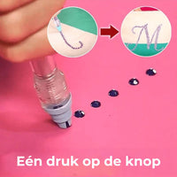 Pen met drukknop pakt een donker steentje op van een roze ondergrond, met voorbeeld van een versierde letter 3