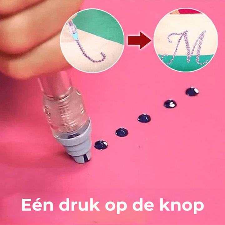 Pen met drukknop pakt een donker steentje op van een roze ondergrond, met voorbeeld van een versierde letter 3