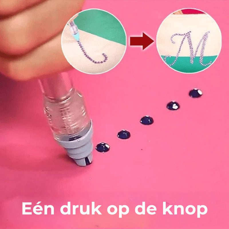Pen met drukknop pakt een donker steentje op van een roze ondergrond, met voorbeeld van een versierde letter 3