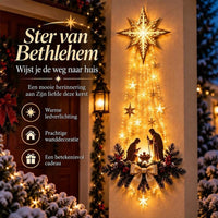 Verlichte gouden ster met lichtslierten en kerststal aan een buitenmuur naast een rode voordeur, met kenmerken ernaast 1