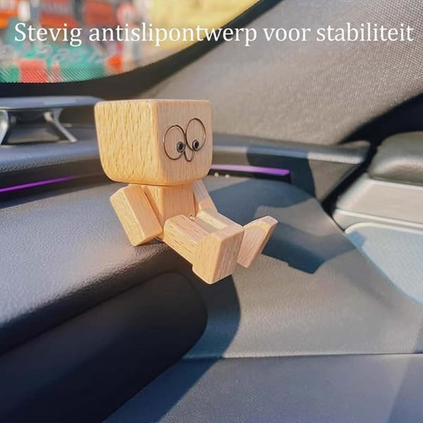 Houten figuurtje met grote ronde ogen zit op een autodashboard en laat zien dat het stevig blijft staan. 12
