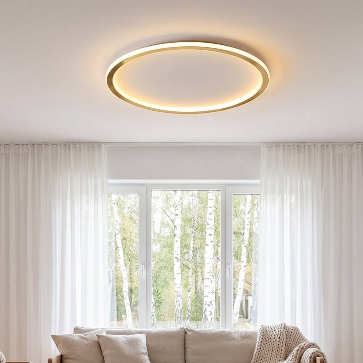 Ronde gouden plafondlamp aan in een lichte woonkamer met bank en witte gordijnen 3