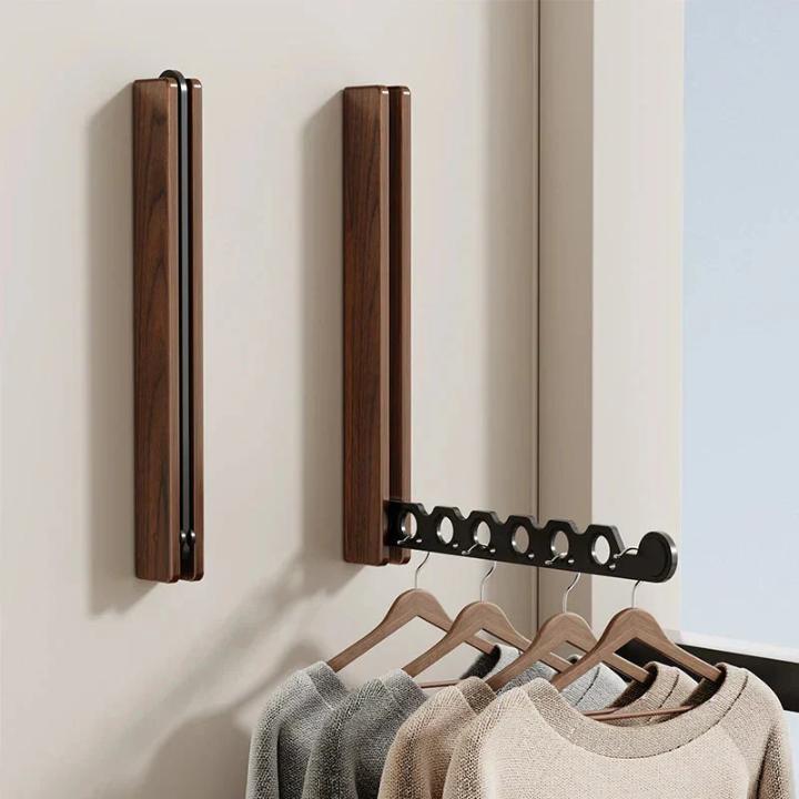 Twee donkerhouten klapkapstokken naast elkaar, links ingeklapt en rechts uitgeklapt met zwarte arm, met vier hangers vol truien. 7