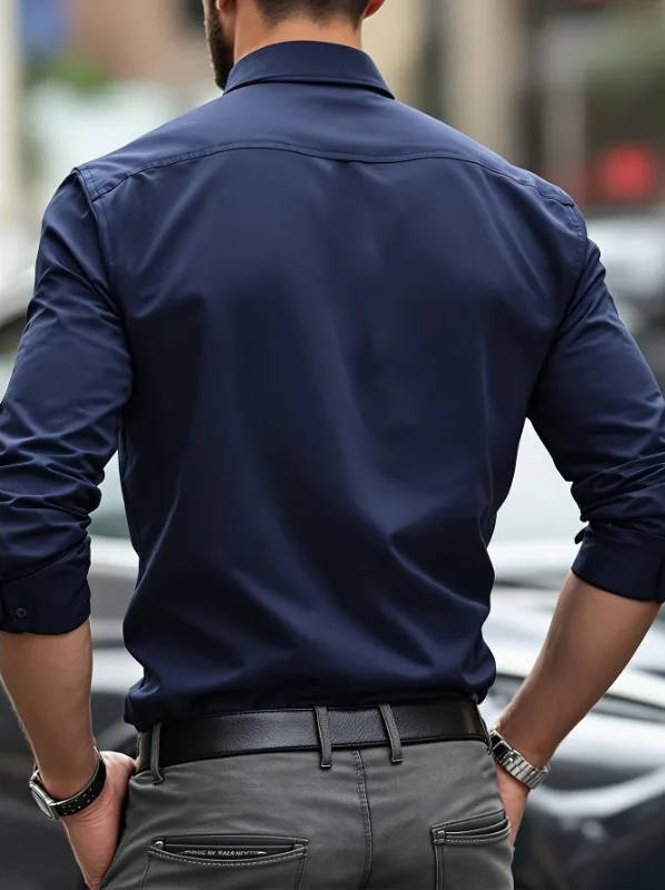 Achterkant van het marineblauwe overhemd aan een model, met schoudernaad en opgerolde mouwen, grijze broek 10