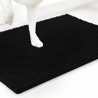 Zwarte variant van de chenille mat met een witte hondenpoot erop, tegen een witte achtergrond. 19