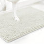 Gebroken witte variant van de chenille mat met een witte hondenpoot erop, tegen een witte achtergrond. 20
