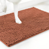 Terracotta variant van de chenille mat met een witte hondenpoot erop, tegen een witte achtergrond. 16