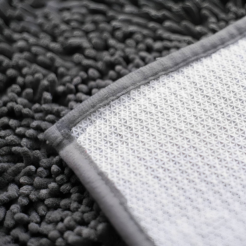 Onderkant van de mat met witte antislip noppenlaag en grijze omgenaaide rand naast de pluizige chenillekant. 8