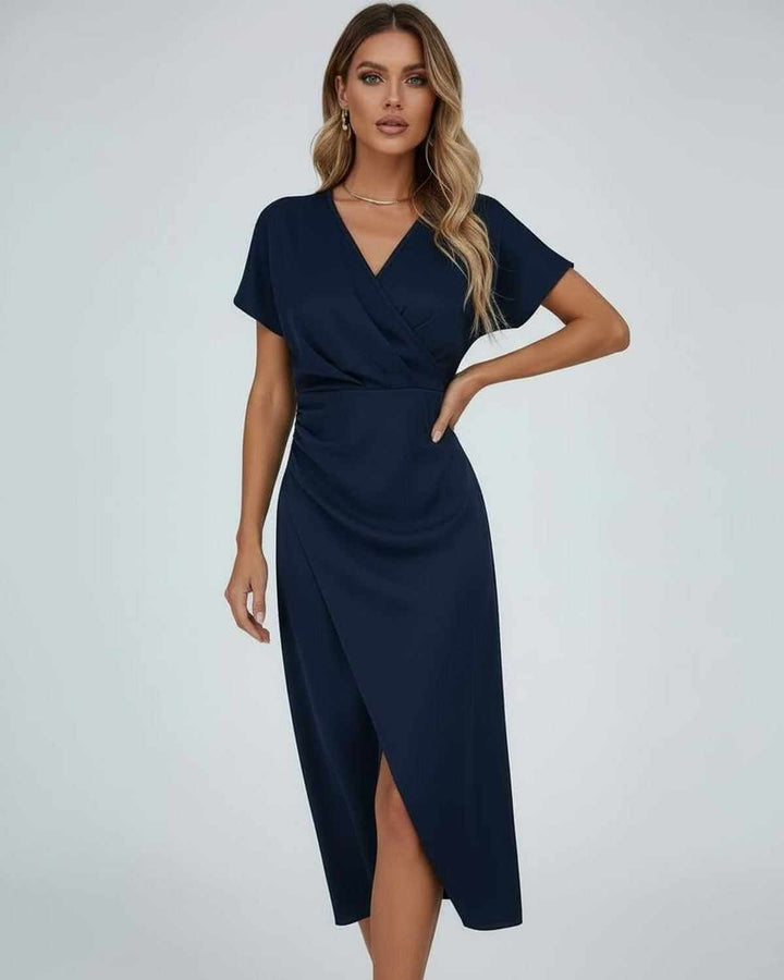 Model in marineblauwe midi-jurk met overslag en gedrapeerde taille, hand op de heup 3