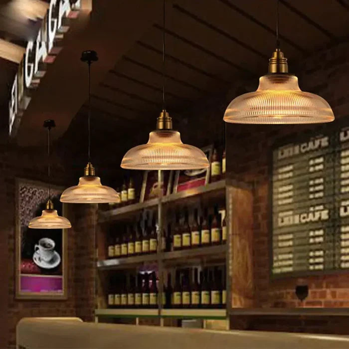 Rij van hanglampen met geribbeld glas boven een bar in een café met bakstenen muur 2