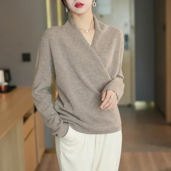 Taupe overslagtrui gedragen met een witte broek, model staat met een hand in de zak 7