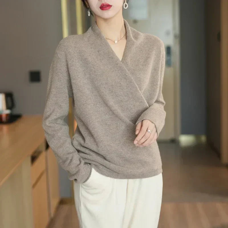 Taupe overslagtrui gedragen met een witte broek, model staat met een hand in de zak 7