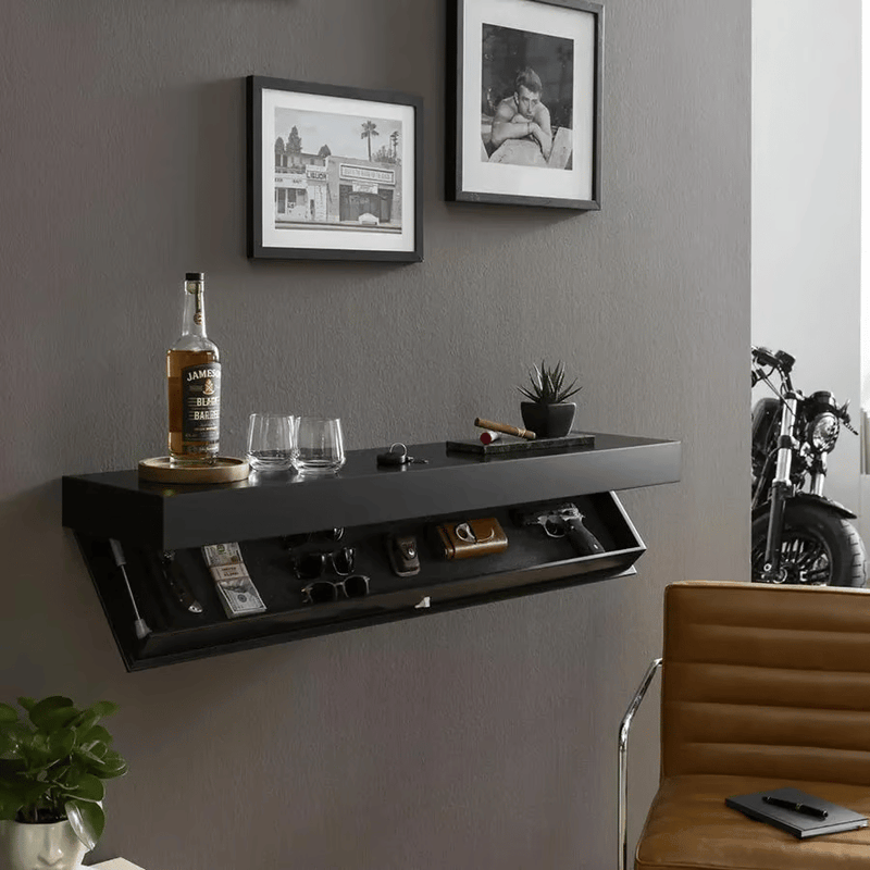 Zwarte wandplank aan een grijze muur in een woonkamer, met open vak vol spullen en een fles en glazen erbovenop. 4