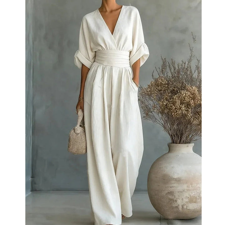 Crèmewitte jumpsuit van voren op een model, nauwer uitgesneden beeld met de gerimpelde taille en wijde pijpen goed zichtbaar. 6