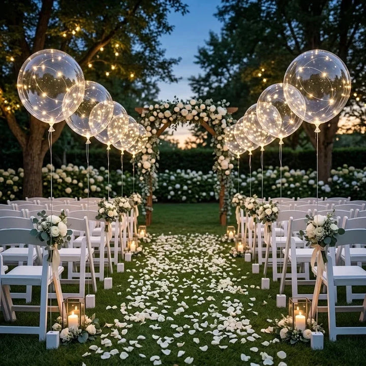 Lichtgevende ballonnen langs het looppad van een tuinbruiloft met witte stoelen, rozenblaadjes en bloemenboog 6