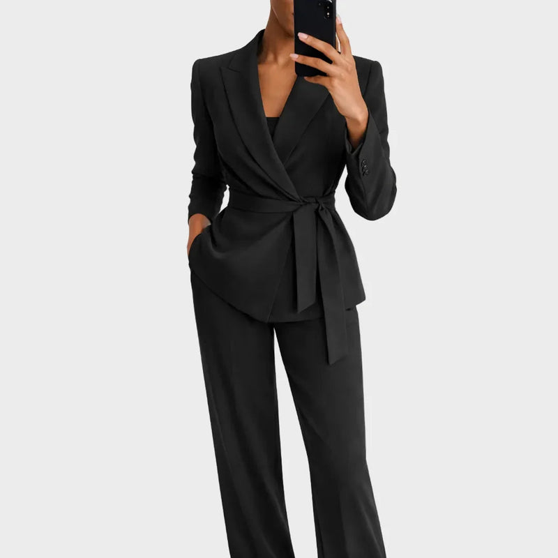 Dezelfde set in zwart, gedragen door een model dat een spiegelselfie maakt, met geknoopte ceintuur en wijde broekspijpen. 3