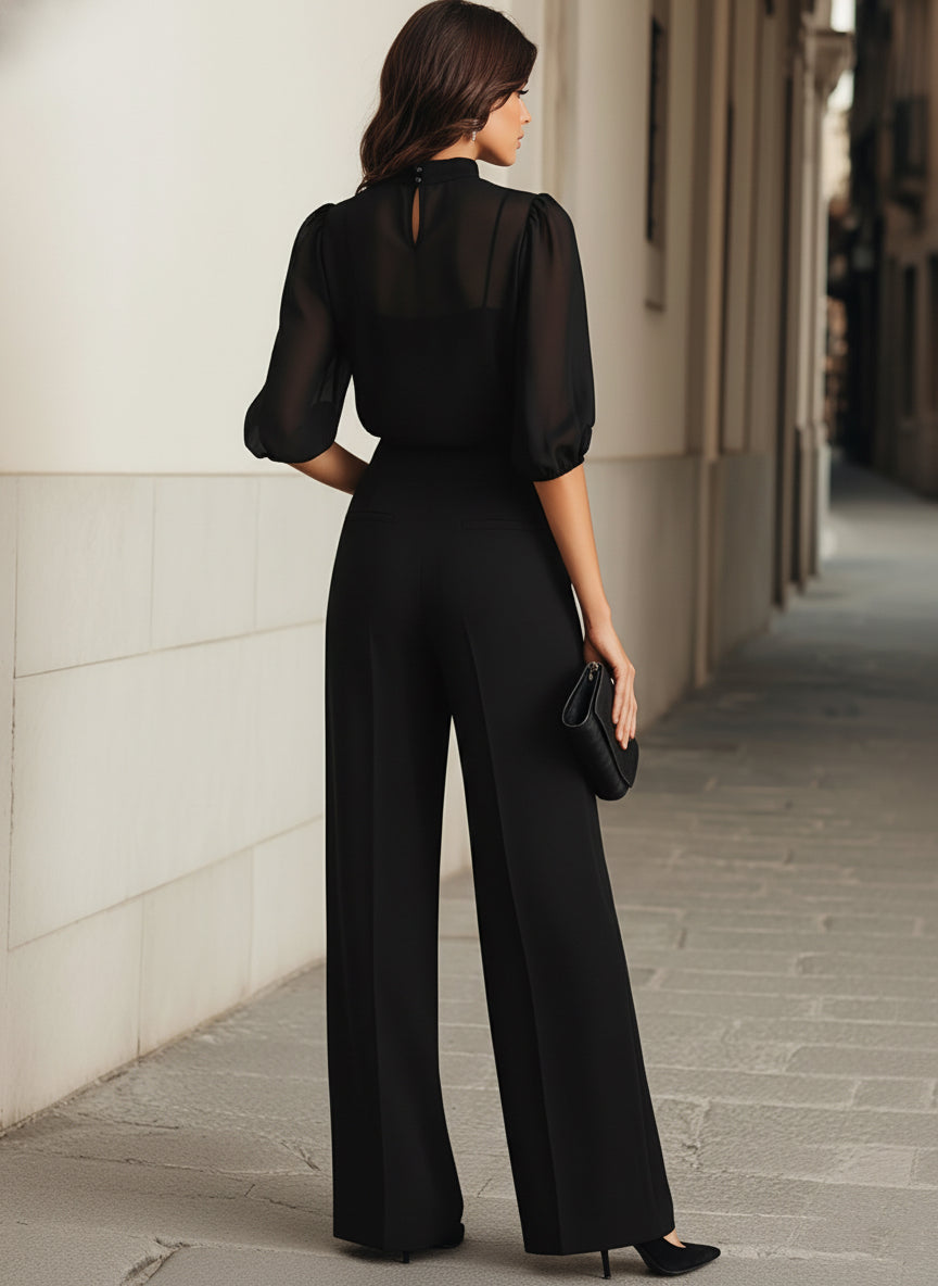 Model van achteren in zwarte set, met doorschijnende rug, sluiting in de nek, pofmouwen en wijde broek. 9