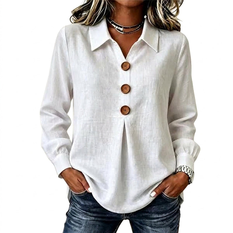 Witte blouse met drie houten knopen, gedragen met een spijkerbroek en handen in de zakken 1