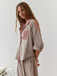 Model in beige roze geruite pyjamaset met roze gestreepte kraag en borstzak, schuin van opzij gefotografeerd met mouwen opgerold. 2